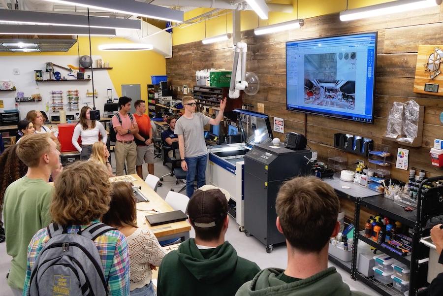 A group of students stand while listening to a presentation in the Dorf Makerspace.